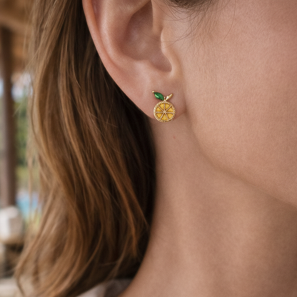 Close-up of a person wearing a gold earring with a Lemon Slice earring.