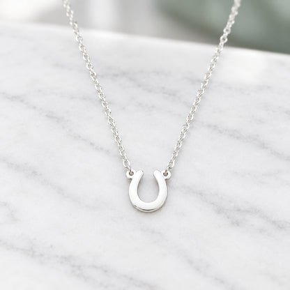 A silver Lucky Horseshoe Necklace on marble