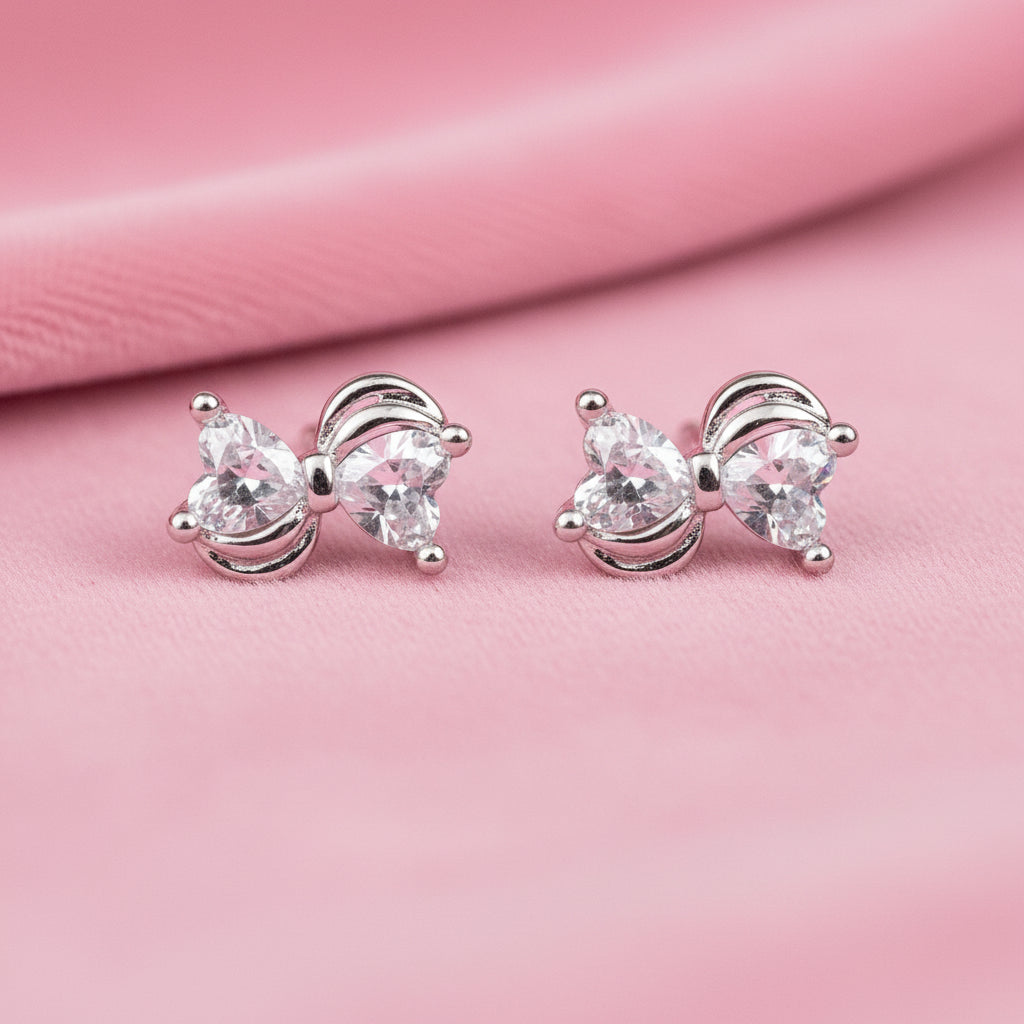 Mini Silver Heart Crystal Bow Earrings on a pink background