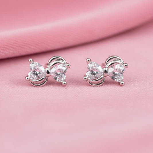 Mini Silver Heart Crystal Bow Earrings on a pink background