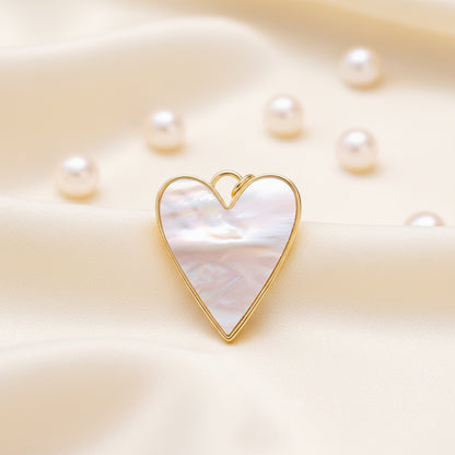 Mother-of-Pearl Heart Charm with gold frame and mother-of-pearl center on a soft beige background.