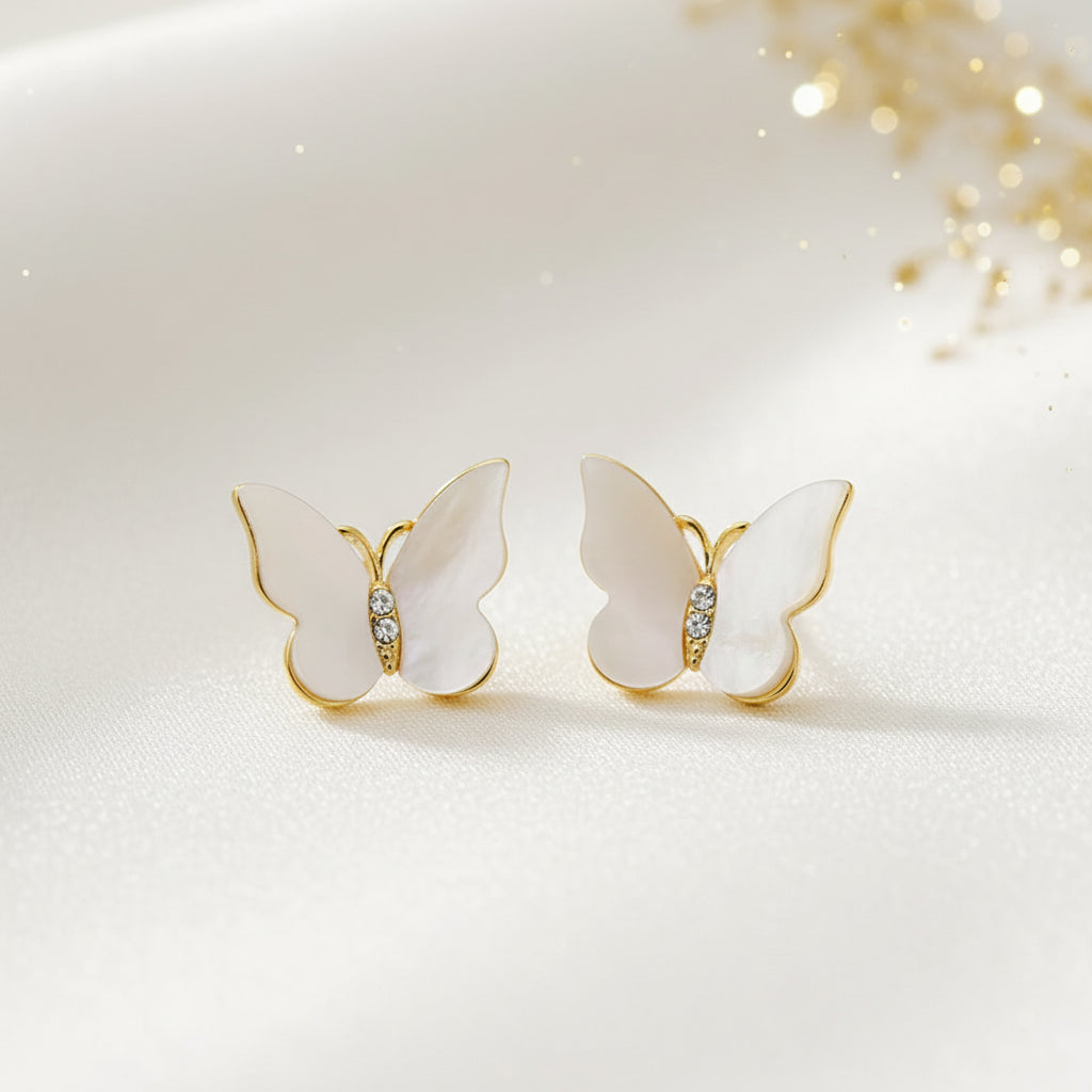 Mother of Pearl Butterfly Earrings with gold and white details on a textured fabric background
