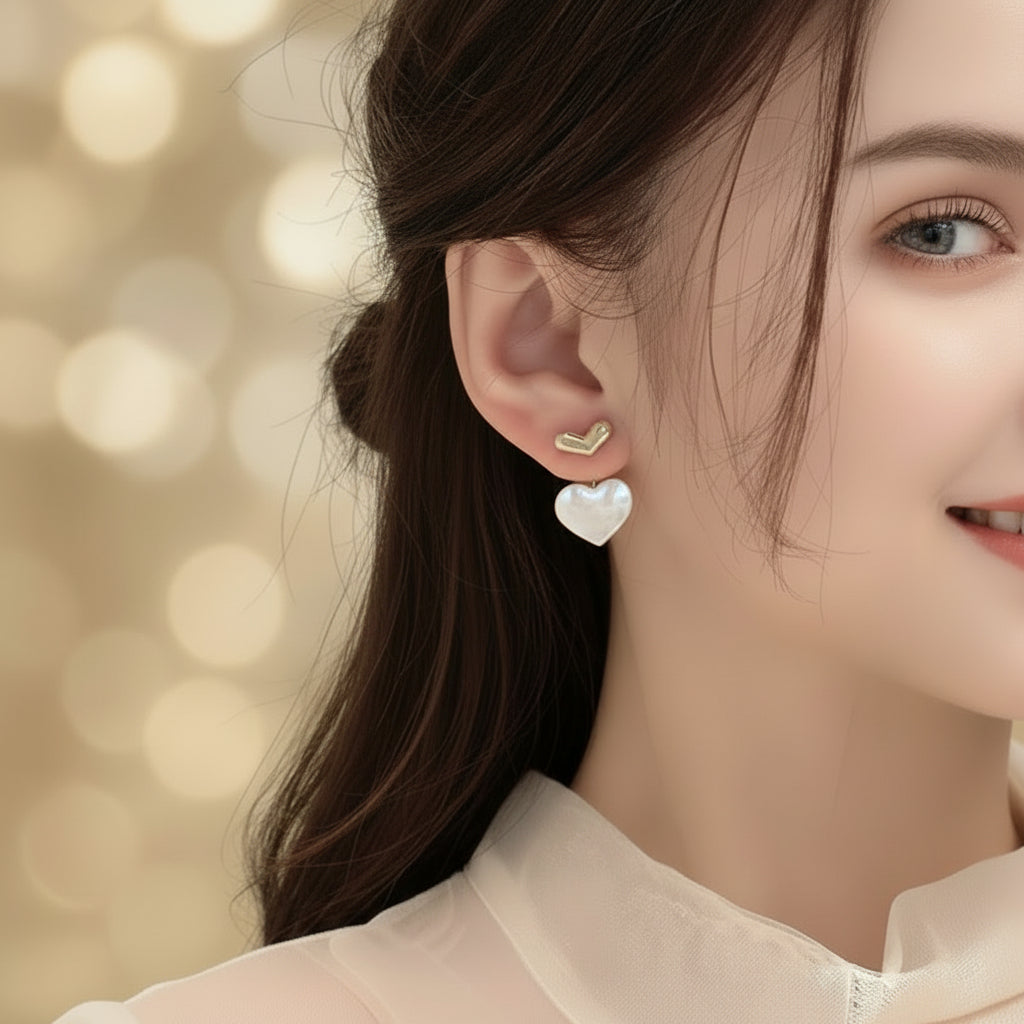 Close-up of a person wearing Mother of Pearl Double Heart Drop Earrings