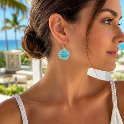 Woman wearing Ocean Mist Sand Dollar Earrings with a tropical background