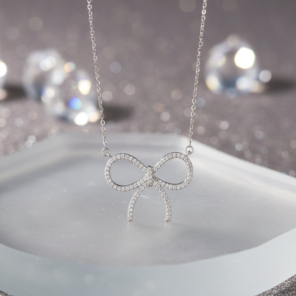 A Pavé Bow Necklace suspended from a delicate silver chain against a plain white background.