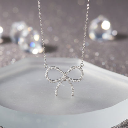 A Pavé Bow Necklace suspended from a delicate silver chain against a plain white background.