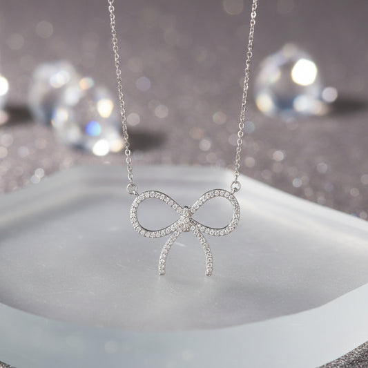 A Pavé Bow Necklace suspended from a delicate silver chain against a plain white background.