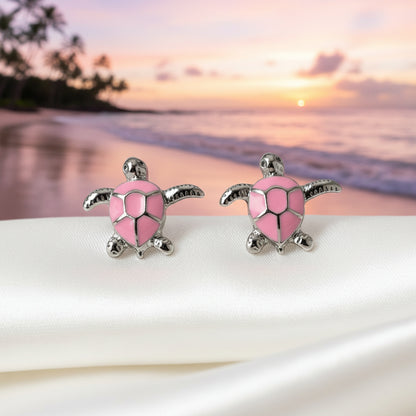 Pink Sea Turtle Earrings on a beach with a sunset in the background