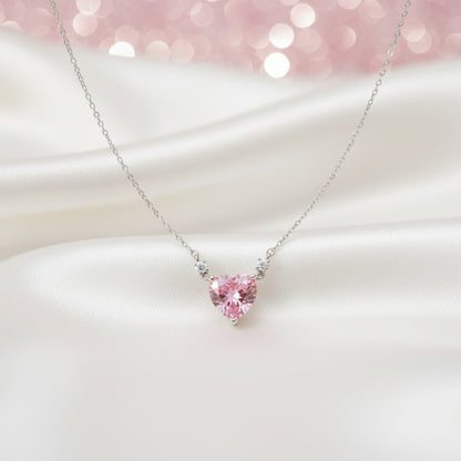 Pink Zirconia Heart Necklace on a white surface with a soft pink blurred background