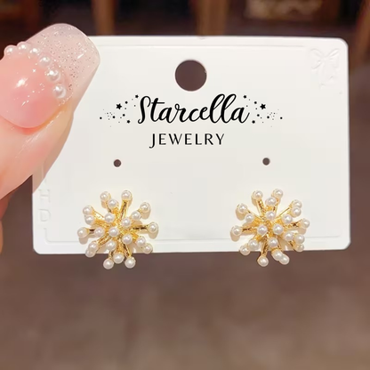 Gold Burst Pearl Earrings on a Starcella Jewelry card held by a hand with pink nail polish.