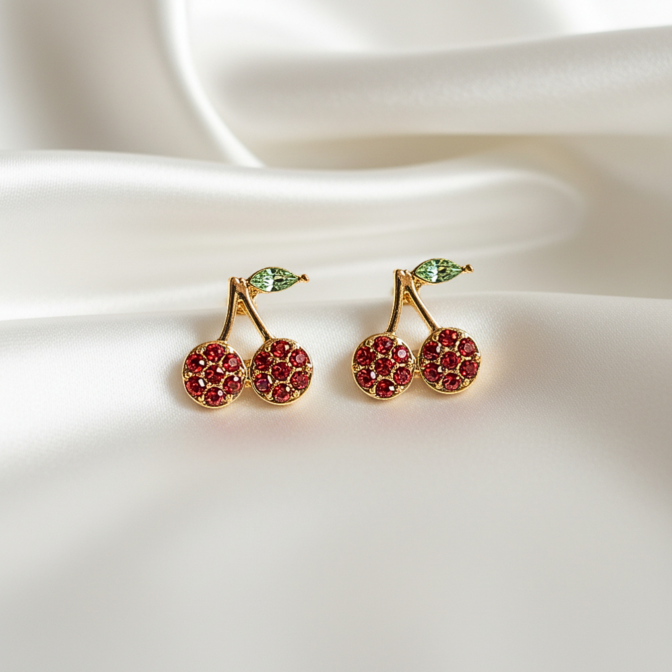 Red Pavé Cherry Earrings on a white fabric background