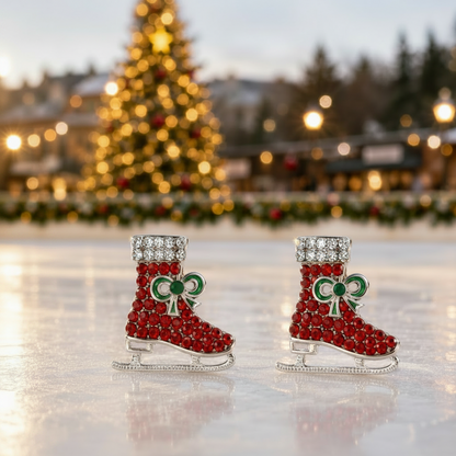 Red Pavé Ice Skate Earringsdisplayed on a reflective ice surface with a blurred Christmas tree and festive lights in the background.