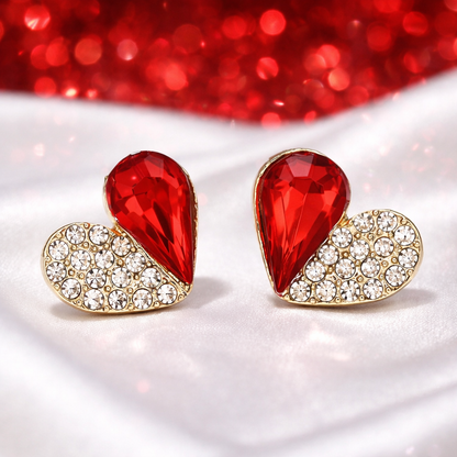 Ruby Crystal Heart Pavé Earrings with red gemstones and gold accents on a red glittery background