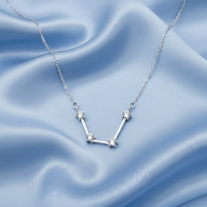 Silver Aquarius Zodiac Necklace with star design on a blue satin background