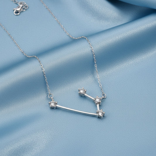 Silver Aries Zodiac Necklace on a blue fabric background