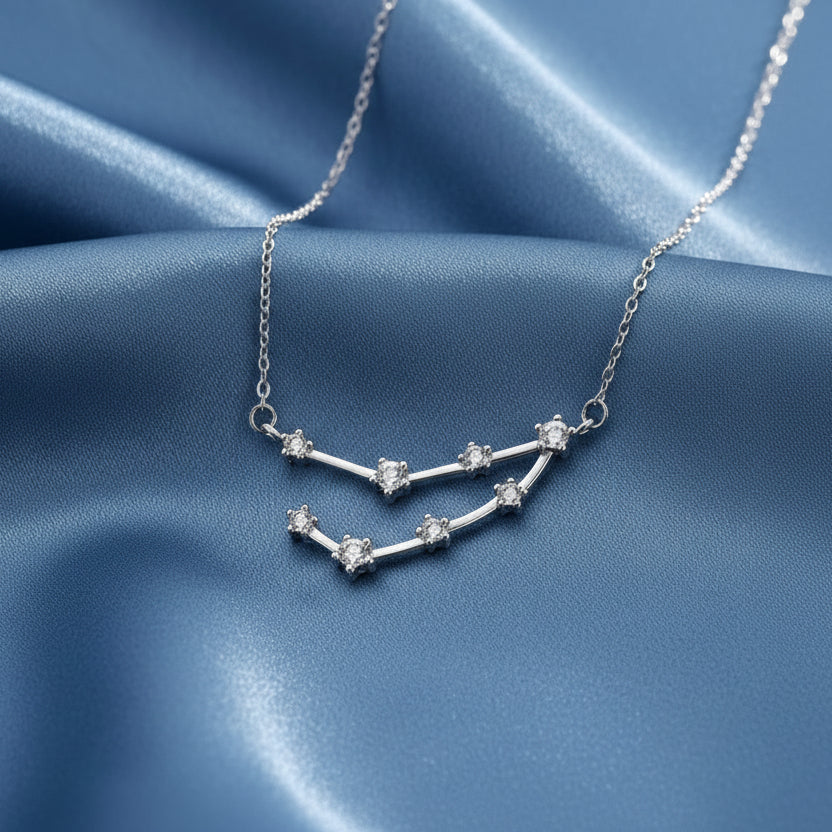 Silver Capricorn Zodiac Necklace with star-shaped pendant on a blue fabric background