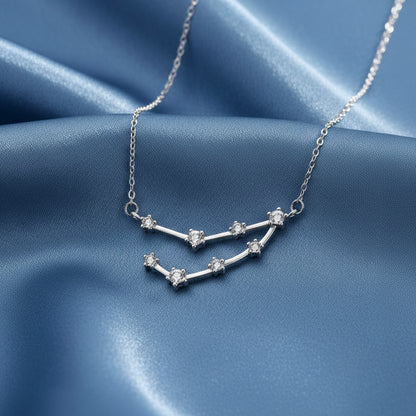 Silver Capricorn Zodiac Necklace with star-shaped pendant on a blue fabric background