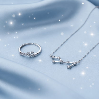 Sterling silver jewelry set featuring a constellations necklace and matching hoop ring, both adorned with small clear cubic zirconia stones, displayed on a soft light blue satin fabric background.
