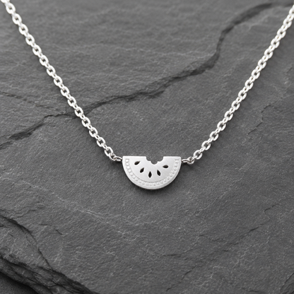 Silver Watermelon Slice Necklace on a dark stone surface