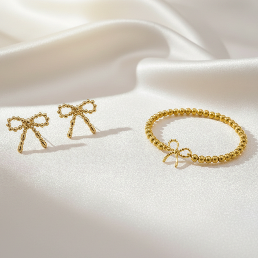 Gold bow-shaped earrings and bracelet on a white and red background