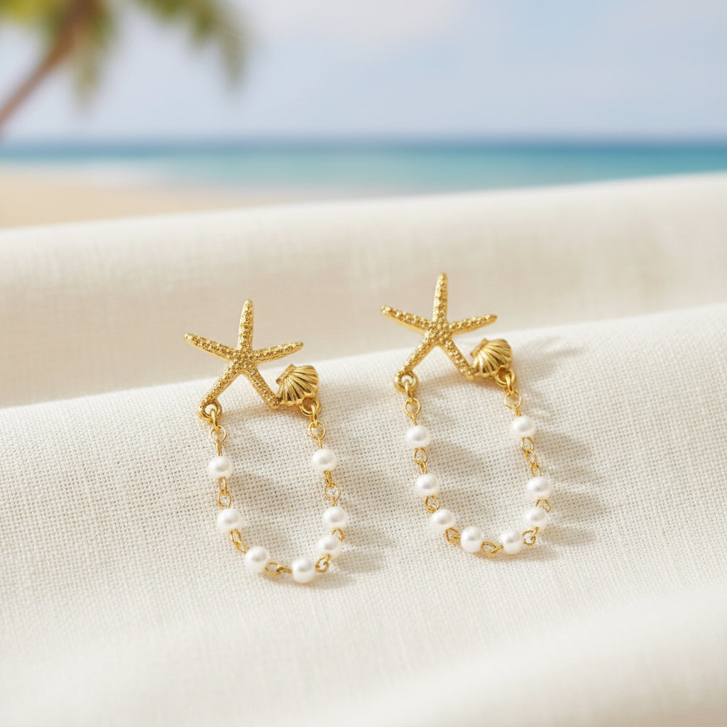 Starfish Shell Pearl Earrings on a textured surface with a beach background.
