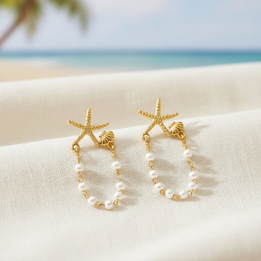 Starfish Shell Pearl Earrings on a textured surface with a beach background.