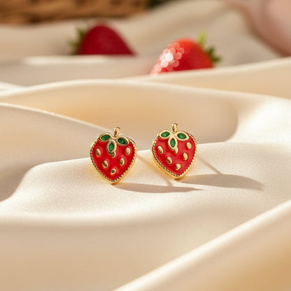 Strawberry Patch Earrings on a white fabric background with strawberries in the background