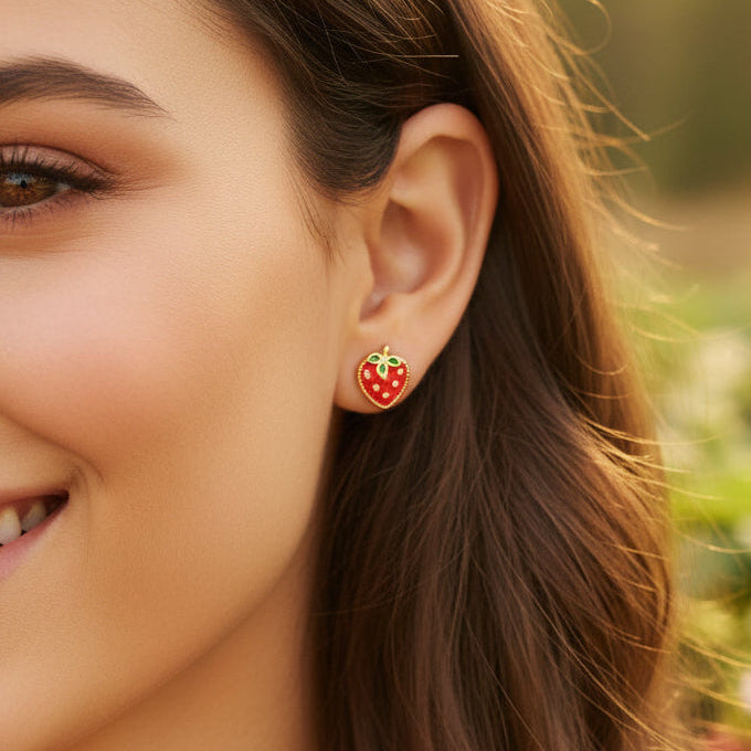 Close-up of a woman wearing Strawberry Patch Earrings with a blurred outdoor background