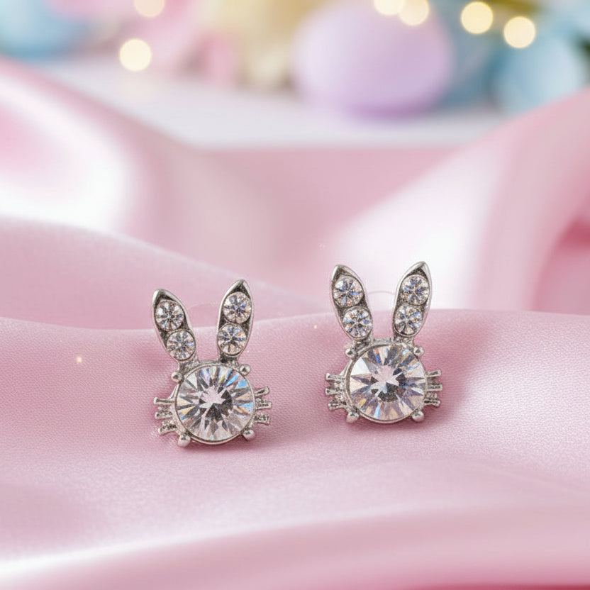 Sweet Bunny Sparkle Earrings with clear gemstones on a pink surface.
