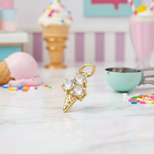Triple Scoop Ice Cream Cone Charm with clear stones on a white surface with ice cream cones and sprinkles in the background.