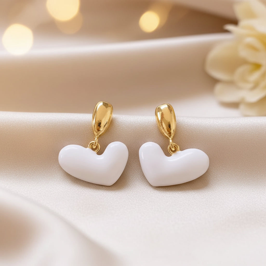 White Heart Drop Earrings on a beige background