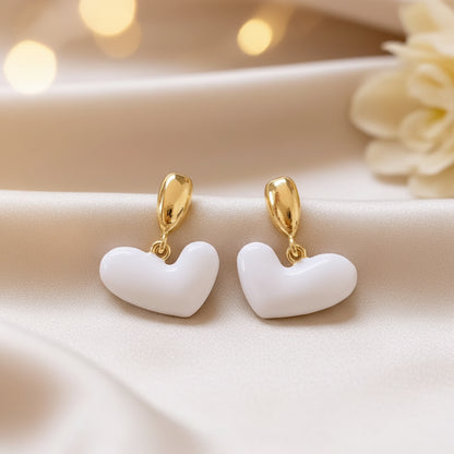 White Heart Drop Earrings on a beige background