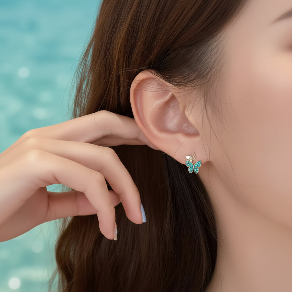 Close-up of a person wearing a Petite Turquoise Double Butterfly Gold Zircon Earring