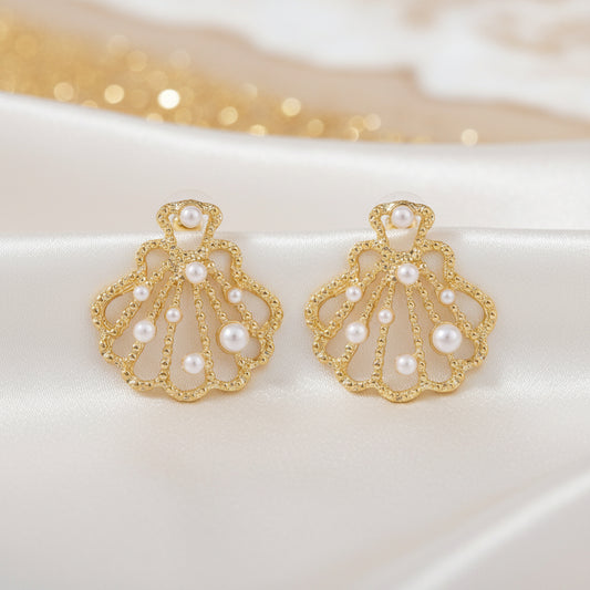 Gold Seashell Pearl Earrings with pearl accents on a white background