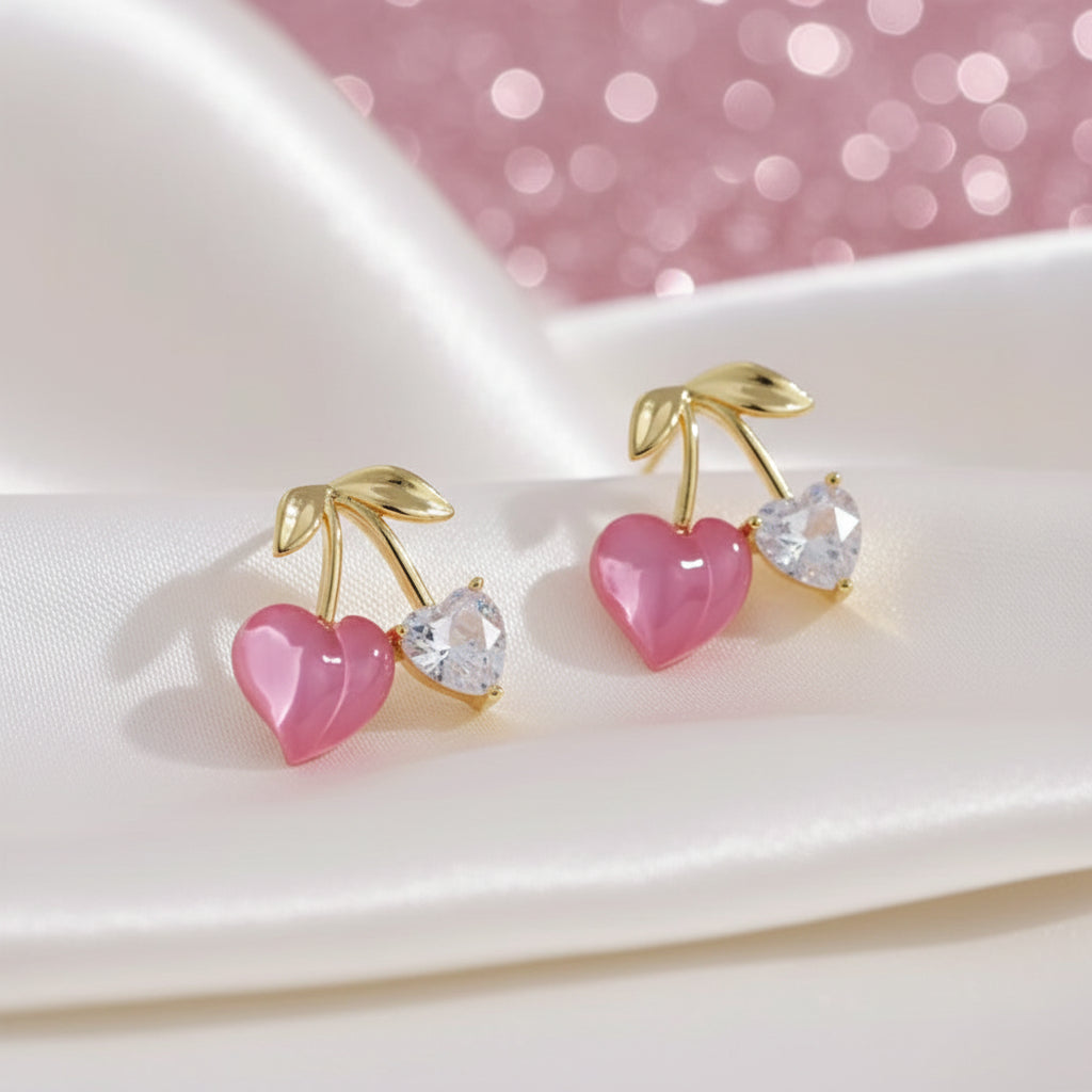 Pink Cherry & Crystal Heart Earrings with pink hearts and gold accents on a white plate.