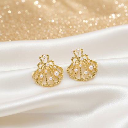 Gold Seashell Pearl Earrings on a textured white surface