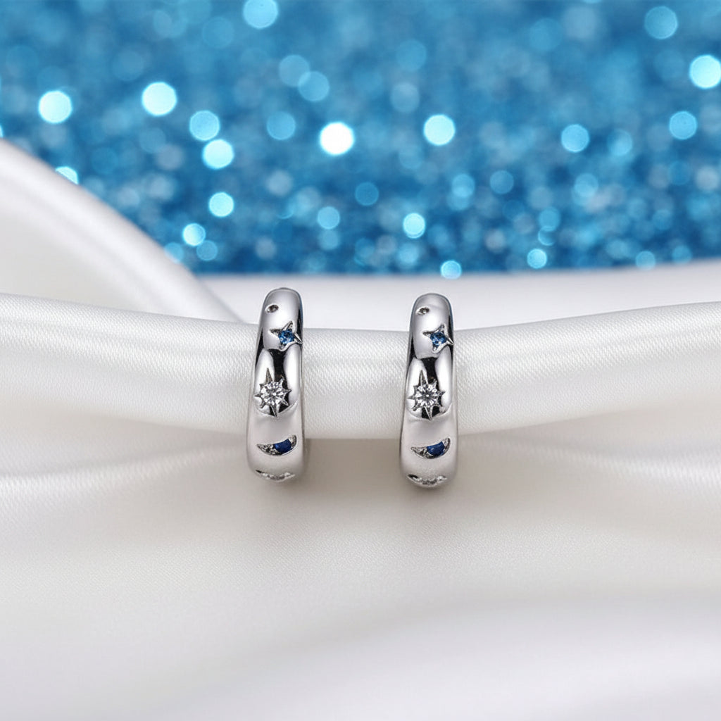 Celestial Star & Moon Hoop Earrings with embedded stones on a white surface