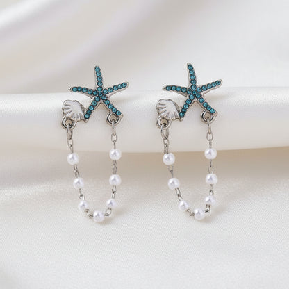Blue Starfish Shell & Pearl Earrings on white fabric