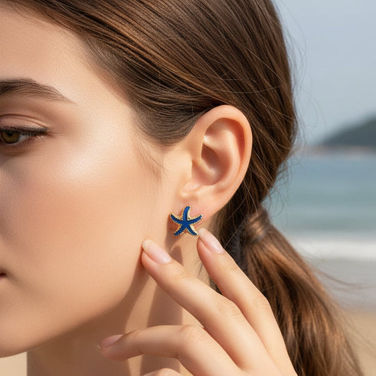 Close-up of a woman wearing Ocean Blue Starfish Earrings with a beach background