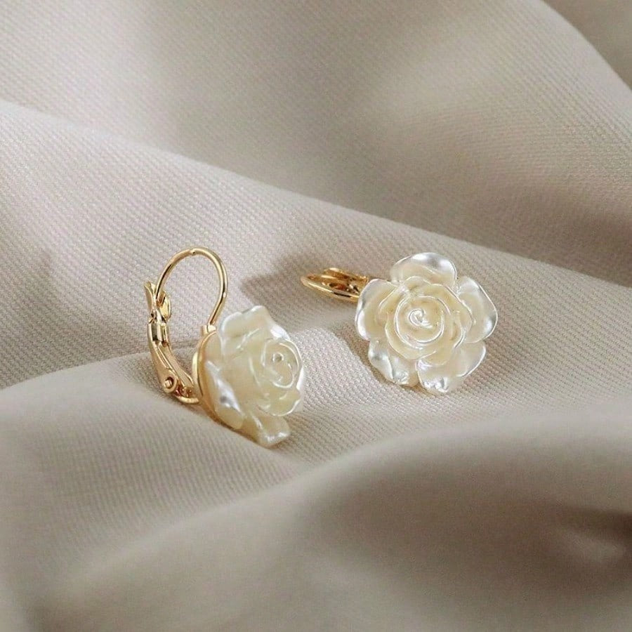 Pair of White Rose Earrings on a beige fabric background