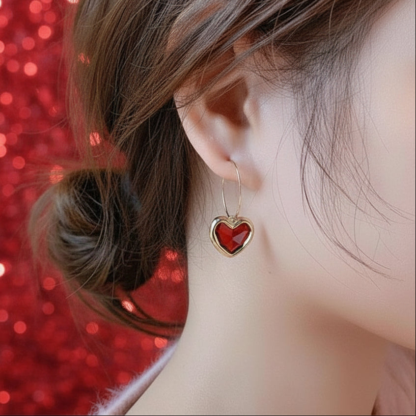 Ruby Heart Hoop Earring worn by a person with a red sequin background