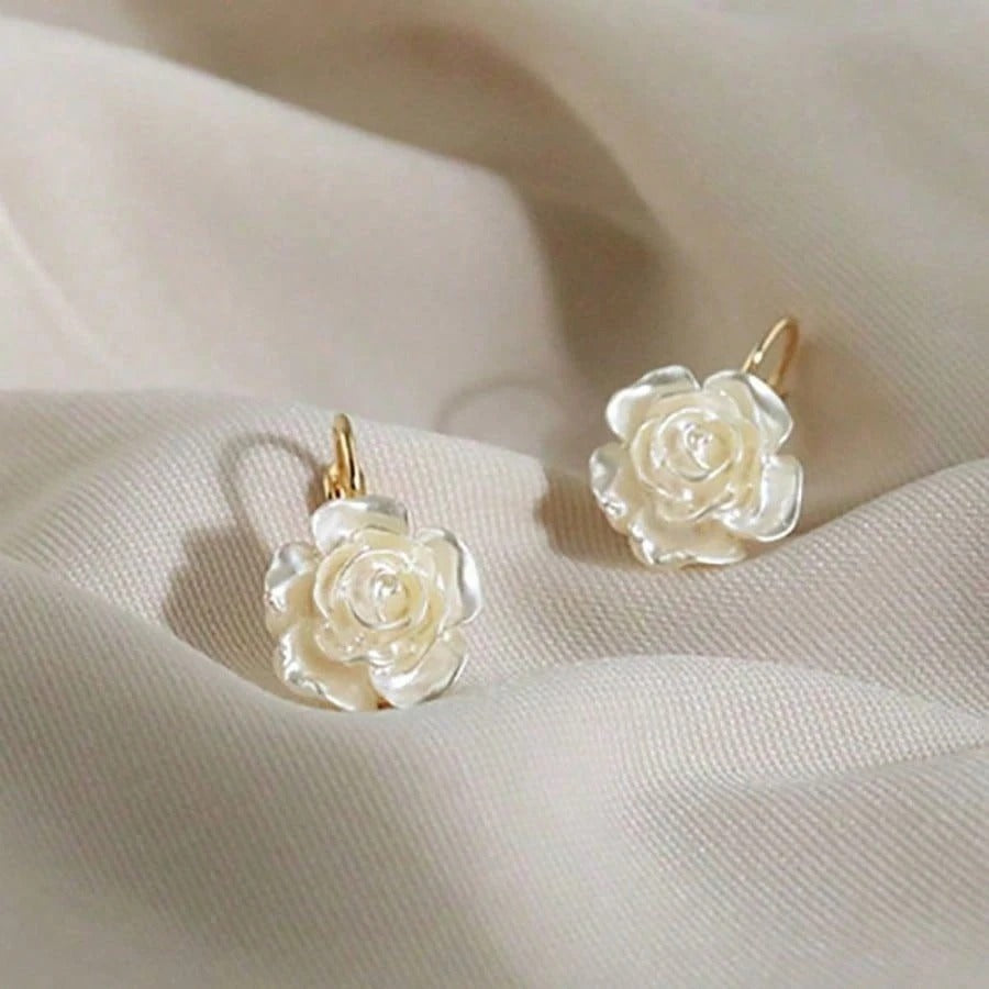 White rose earrings on a soft beige fabric background