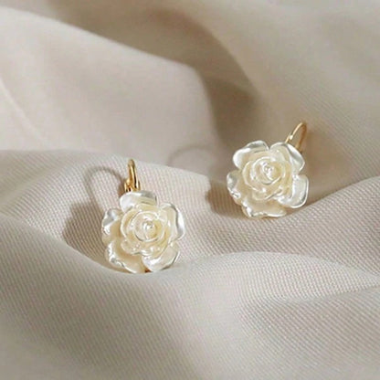 White rose earrings on a soft beige fabric background