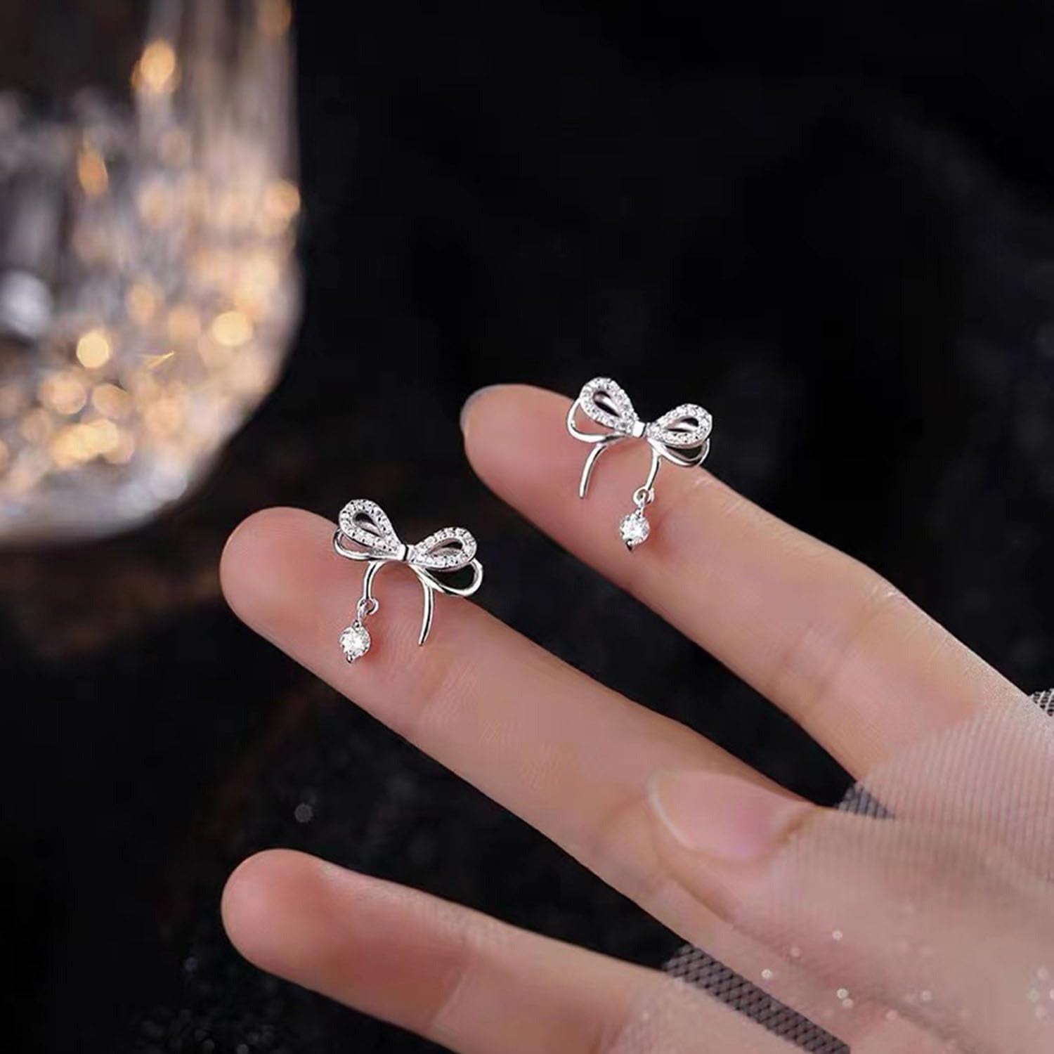 Silver Bow Earrings on a hand with a blurred background