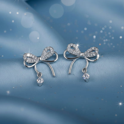 Silver Bow Earrings with small beads on a beige background