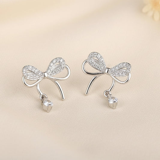 Silver Bow Earrings with small beads on a beige background