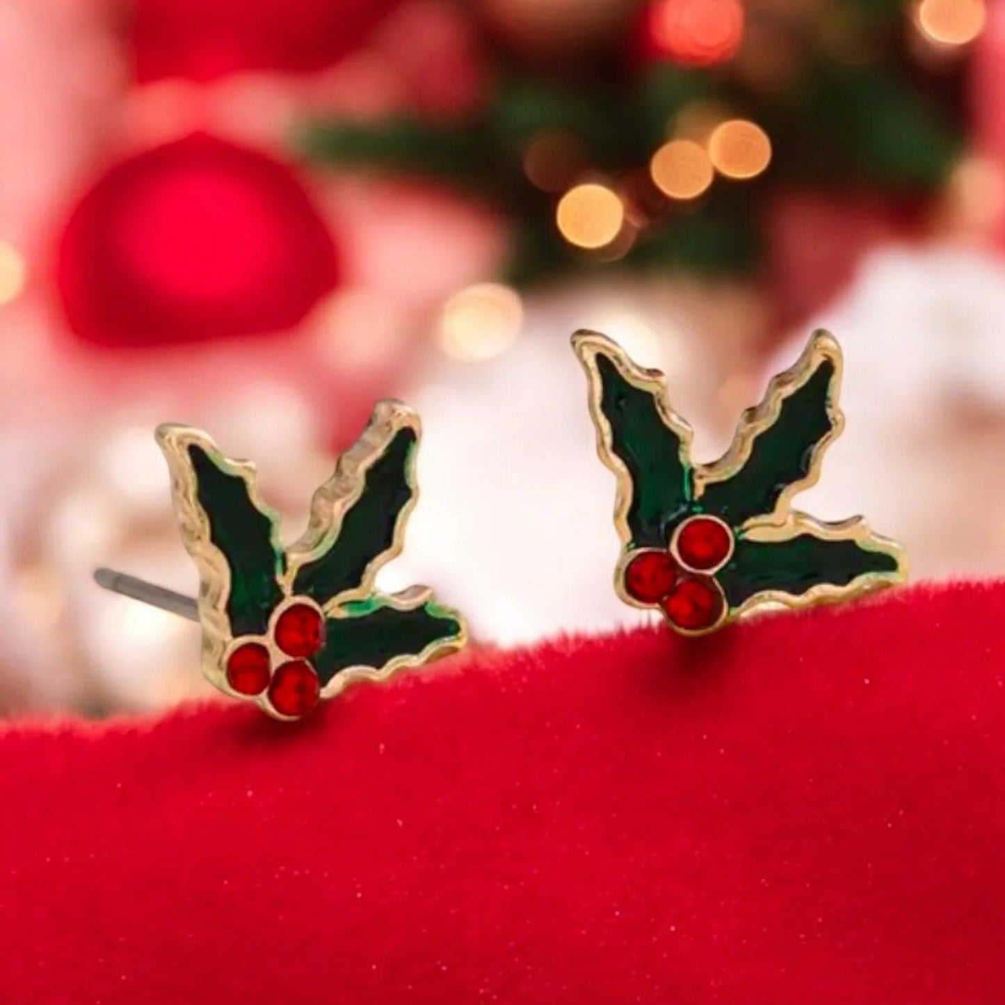 Red Berry Holly Earrings on a red surface with a blurred festive background