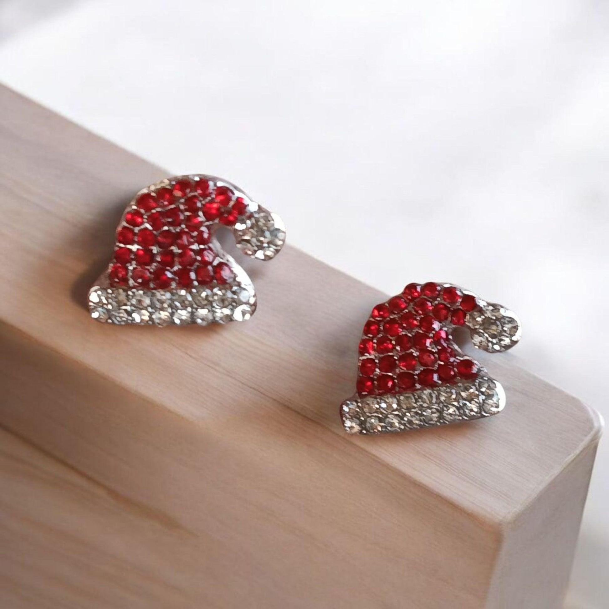 Santa Hat Rhinestone Earrings on a wooden block with a white background