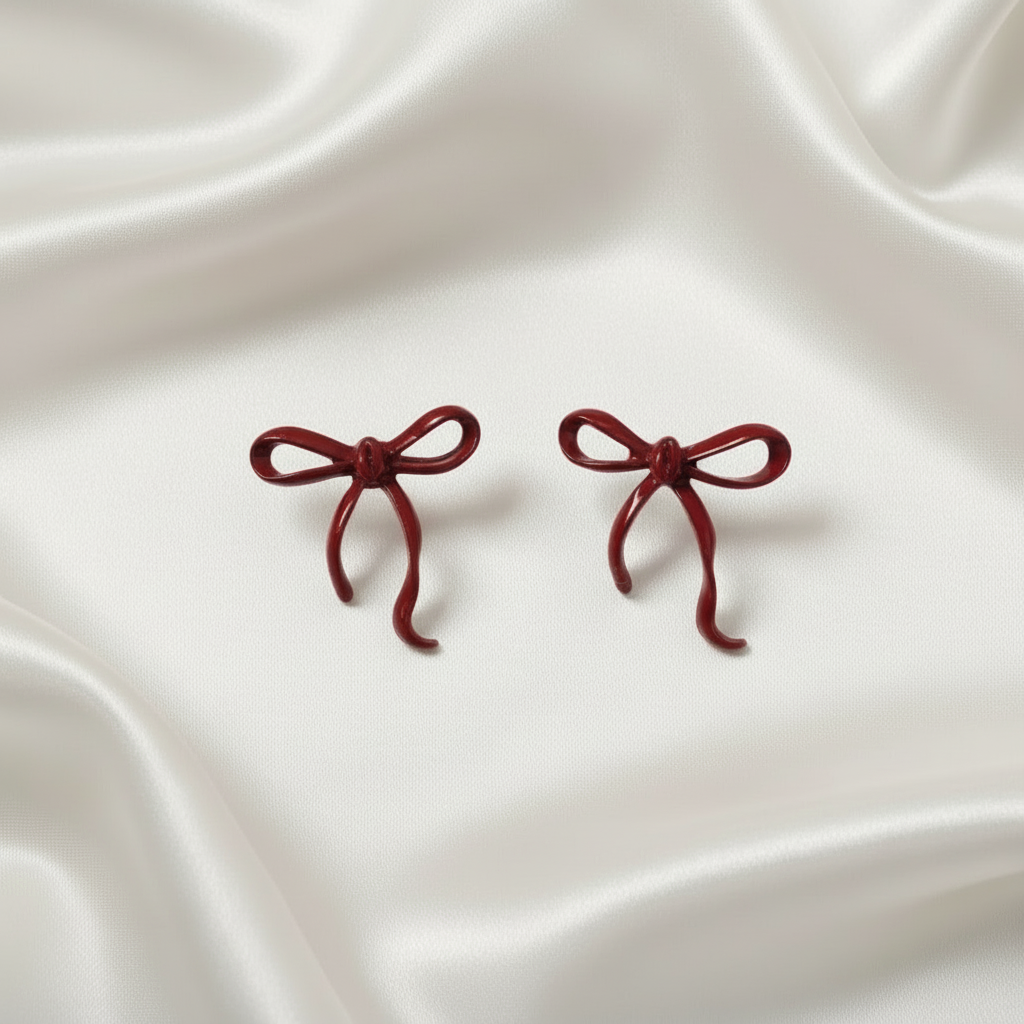Crimson Bow Earrings on a white satin background