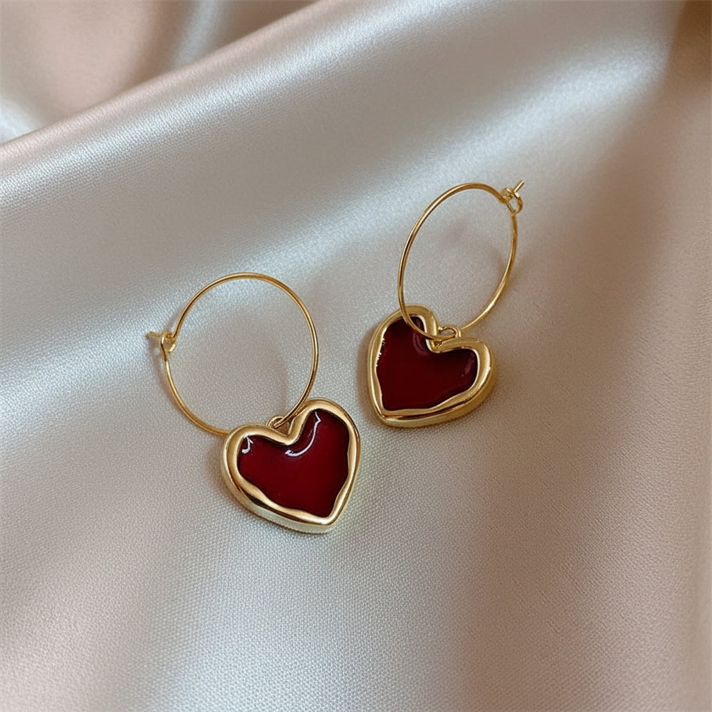 Ruby Heart Hoop Earrings with red centers on a satin surface